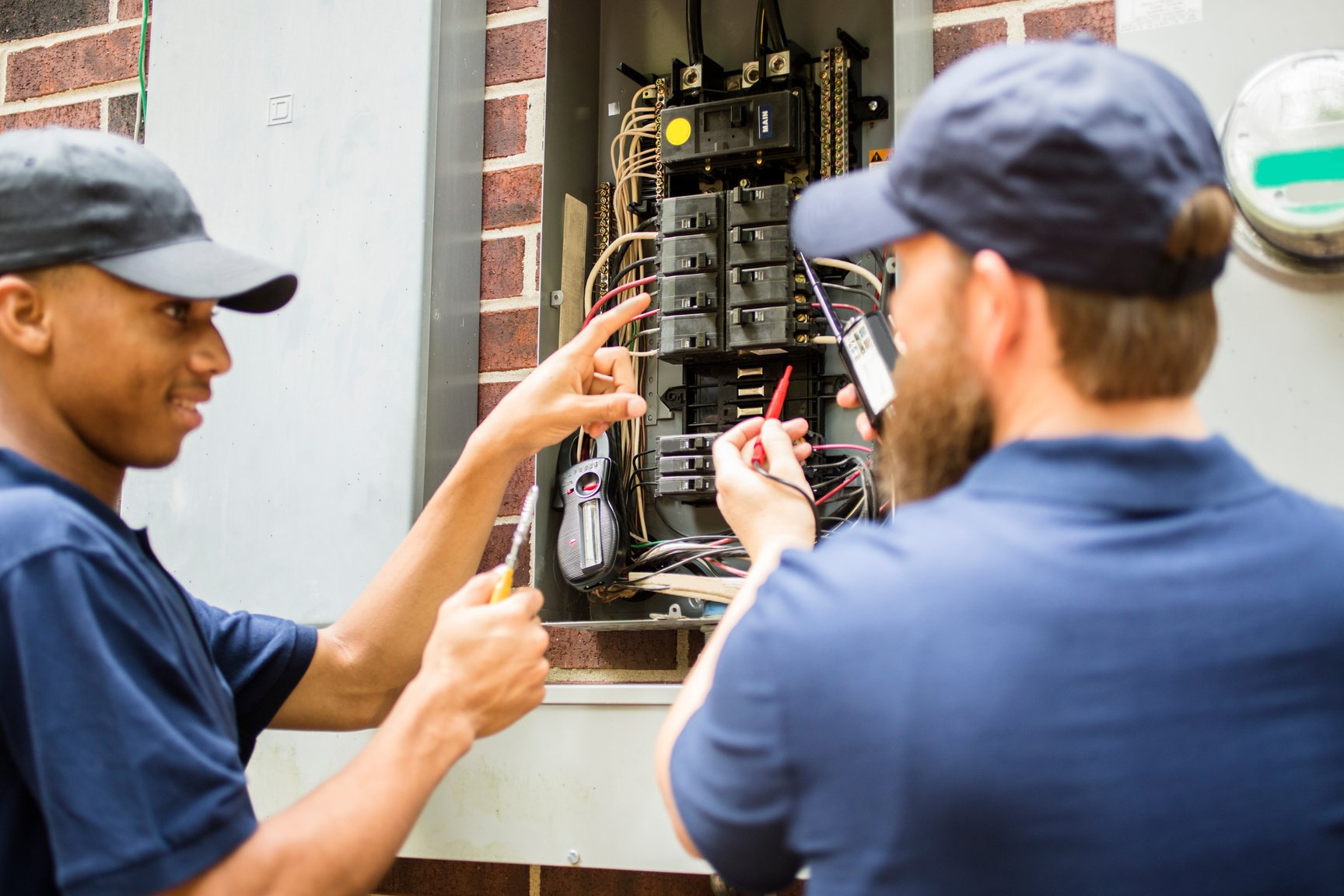 Repairmen, electricians repairing home breaker box.